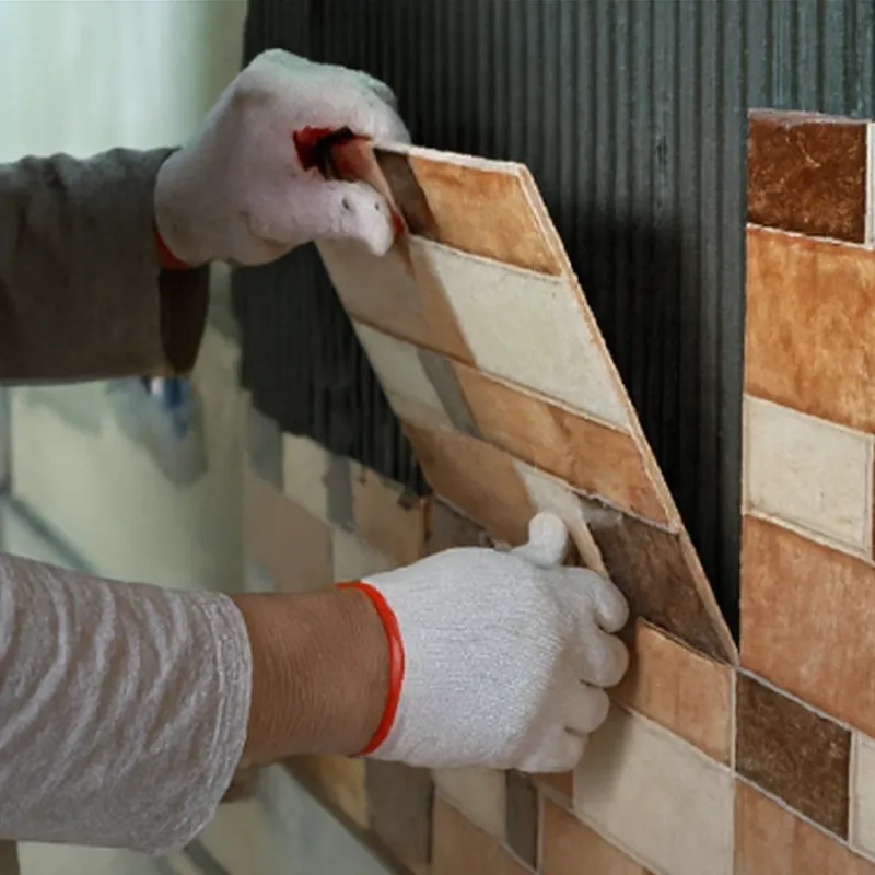 Gloved hands installing wall tiles